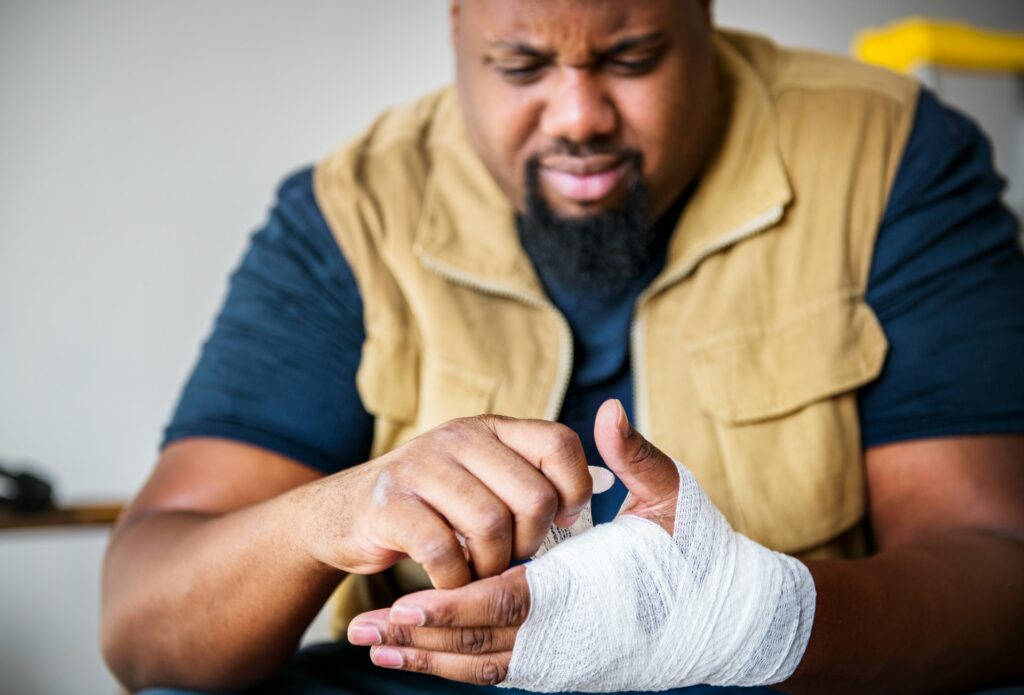 Man with a bandaged hand examining his injury, representing personal injury claims and recovery in legal context.