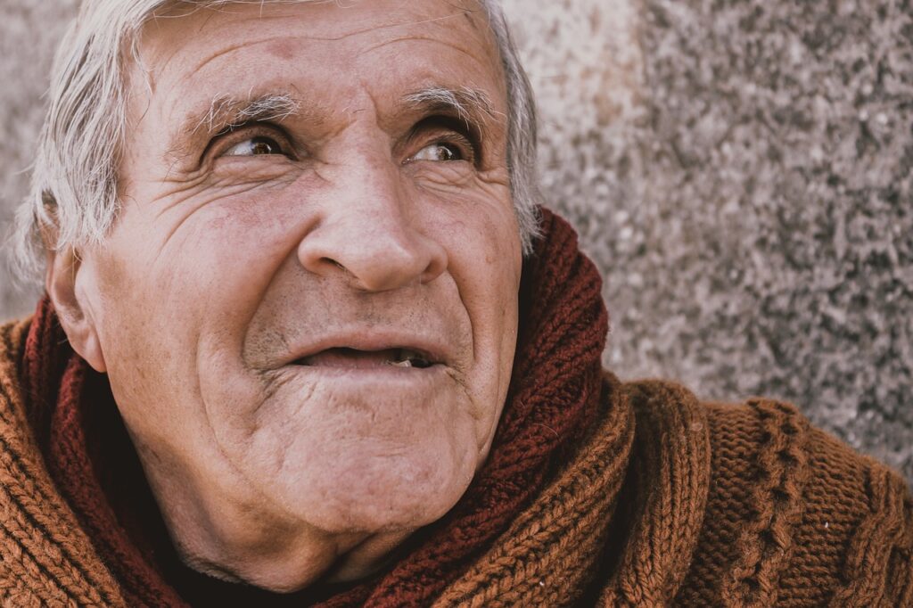 Elderly man smiling warmly, wearing a cozy brown sweater, representing the importance of elder law and care for seniors in legal contexts.