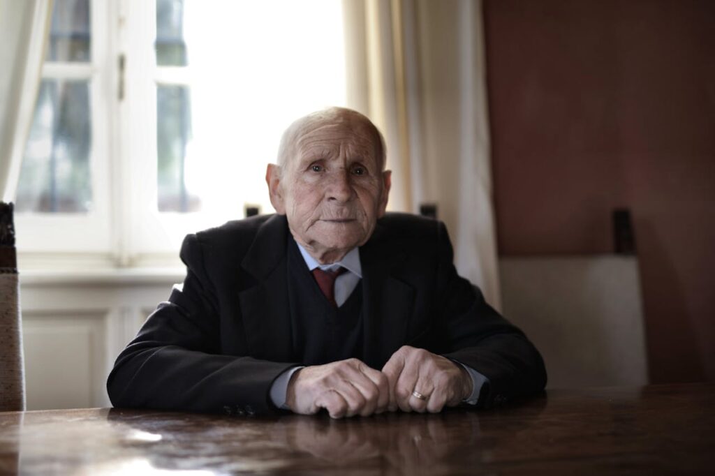 Elderly man in formal attire sitting at a table, emphasizing themes of elder law and retirement planning.
