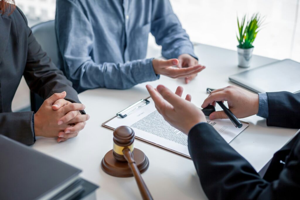 Business professionals discussing legal documents with a gavel and plant on the table, illustrating the importance of legal guidance in business lawsuits.