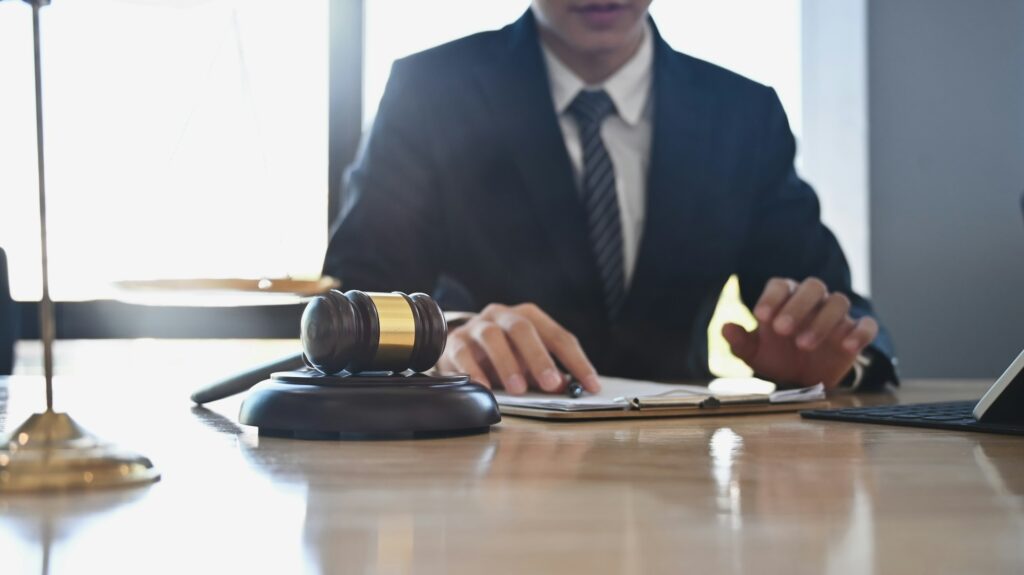 Lawyer in a suit at a desk with a gavel, notebook, and laptop, representing criminal defense legal services in Tulsa, Oklahoma.